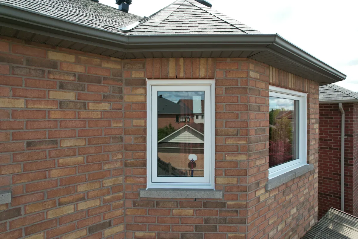 Close-up of new black-framed casement windows set into the brick exterior of an older Toronto home