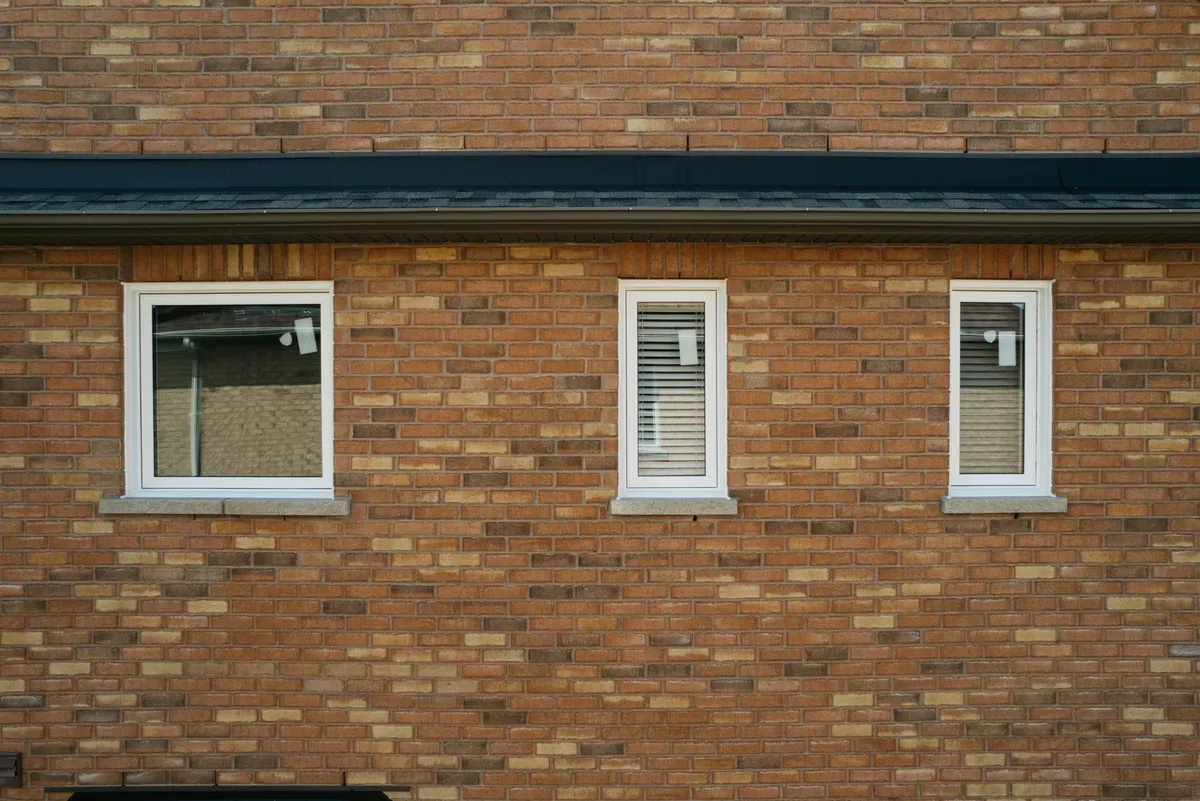 Three new white-framed replacement windows set into the brick wall of a GTA home